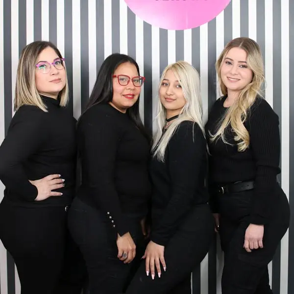 Equipo de profesionales de Rock Up Lash & Brows, posando frente a un fondo de rayas blancas y negras.