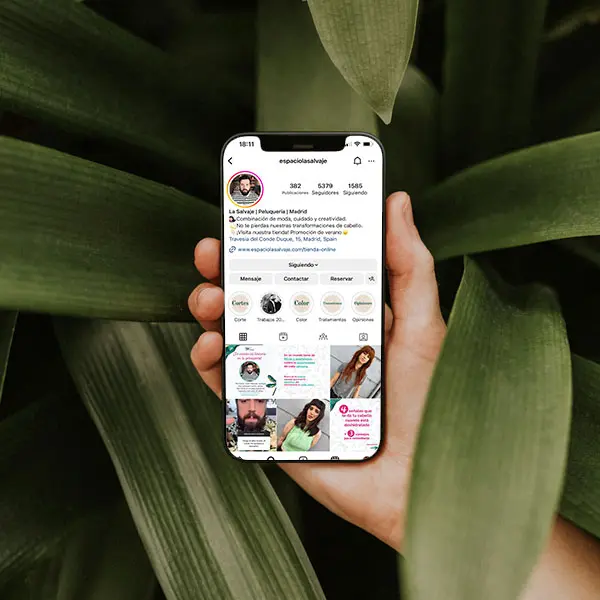Perfil de Instagram de La Salvaje, peluquerÃƒÂ­a en Madrid, mostrado en un telÃƒÂ©fono mÃƒÂ³vil sobre un fondo de hojas.