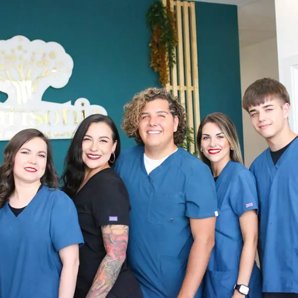 Equipo de profesionales de Adansonia Centro EstÃƒÂ©tico, posando frente al logo del centro en Rivas-Vaciamadrid.